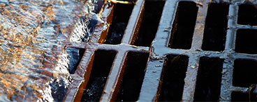 image of runoff water flowing into a storm drain 